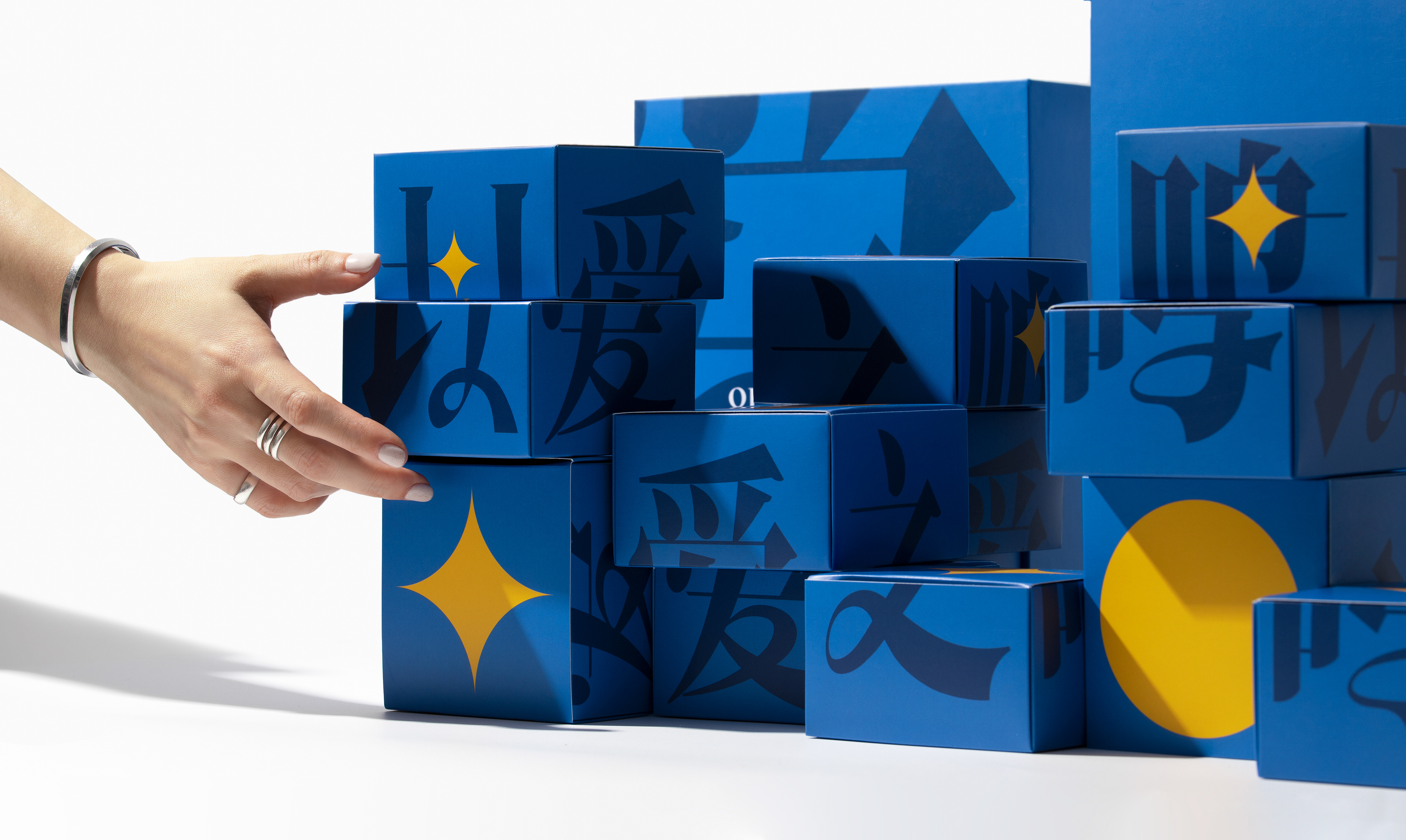 Blue 2023 Love of Mingshi gift boxes with lettering and yellow geometric graphics.